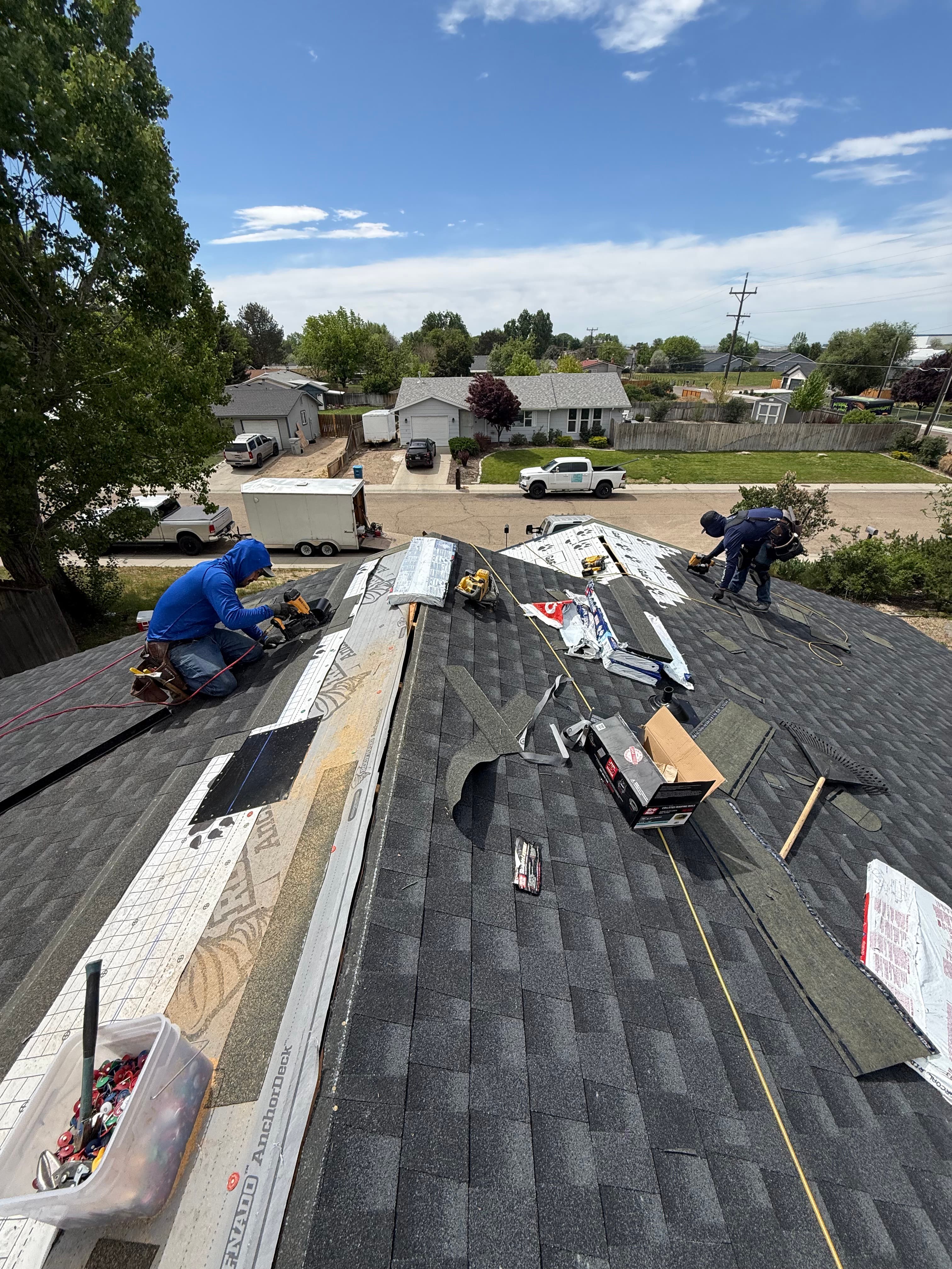Roofing crew installing new architectural shingles on a residential roof